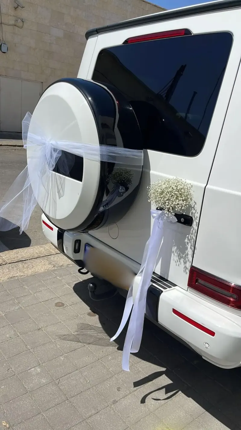 ג'יפ לבן מקושט בסרטים ובפרחים על הגלגל האחורי